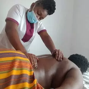 A home massage therapist with Viv's in-Houz Spa, a mobile wellness spa in Nairobi, giving back massage to a client.