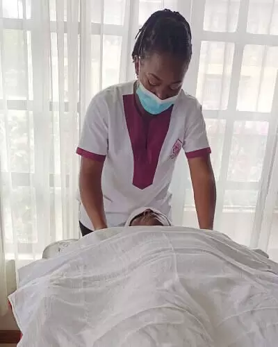 Vivian, a massage therapist from Viv's in-Houz Spa, a mobile spa in Nairobi, and a client laying on the massage table, about to begin massage therapy