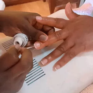 Fidelis, a nail technician with Viv's in-Houz spa; a mobile nail salon in Nairobi applies a French manicure to a client during a home gel manicure and pedicure appointment