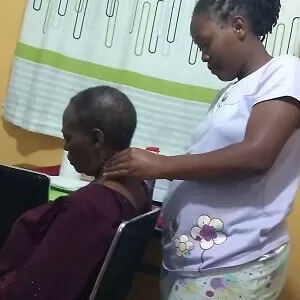 Vivian, a home massage therapist in Nairobi, massaging her mother's neck.