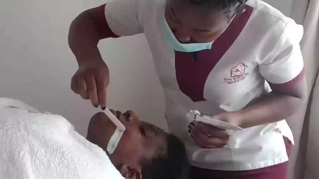 Beautician applying face mask in a deep cleanse facial treatment at a client's home in Nairobi