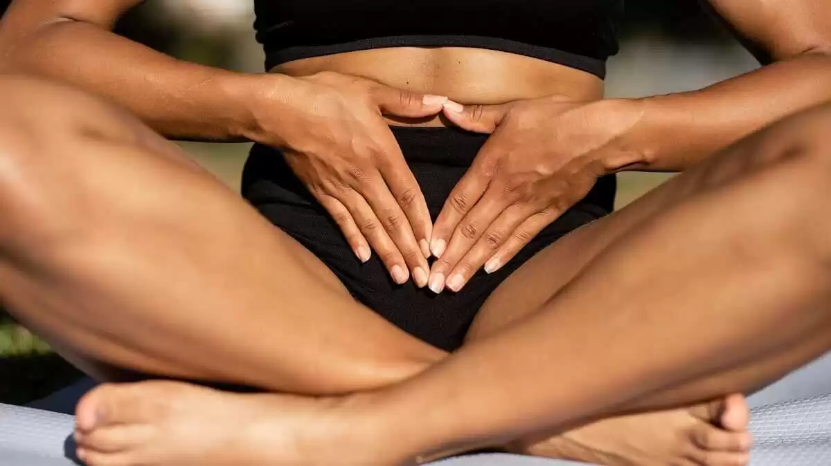 A female groin in black underwear sitting with legs crossed depicting readiness for Brazilian waxing